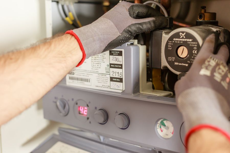 Technician servicing a home furnace and heating system controls