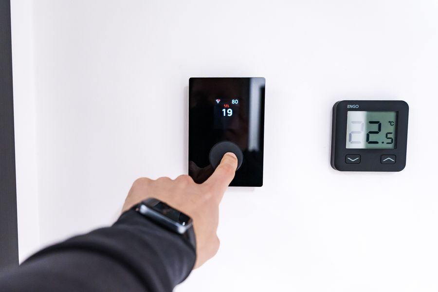 Technician adjusting a modern smart thermostat during a diagnostic visit