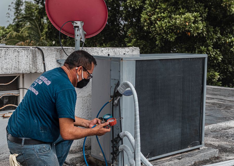 South Bay Heating & Air technician servicing an outdoor AC condenser unit with a manifold gauge